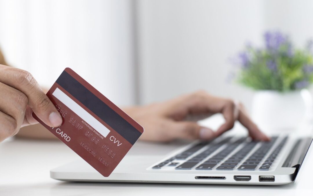 woman holding credit card and looking at laptop